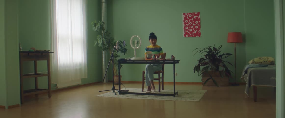 Young woman applying make up on a desk at home in front of a camera