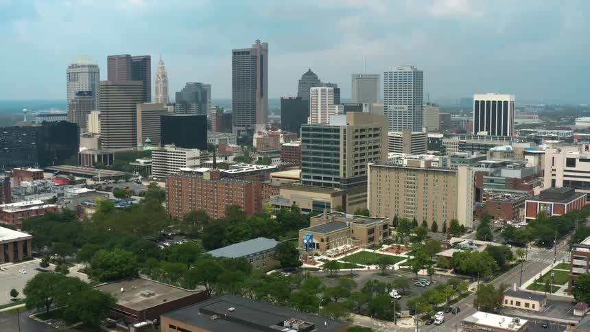Traffic moves along streets around city downtown under heavily clouded sky