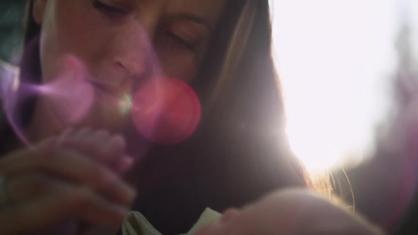 A young woman looks down at her young child as she holds its hand