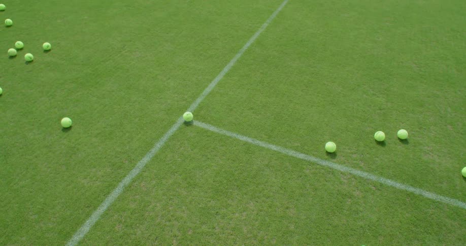 Tennis balls bouncing and rolling onto a grass tennis court