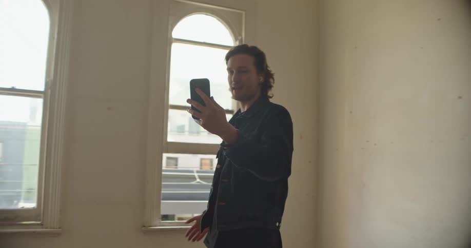A man shows off his new apartment in a video call on his smartphone