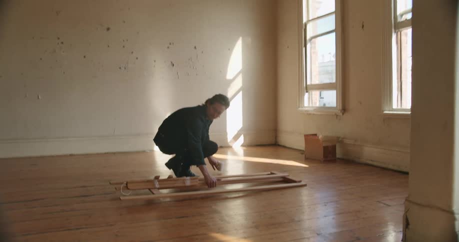 Man carrying an easel into an empty apartment