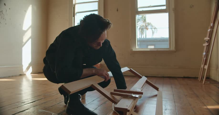 Young man assembling an easel on the floor of an empty apartment