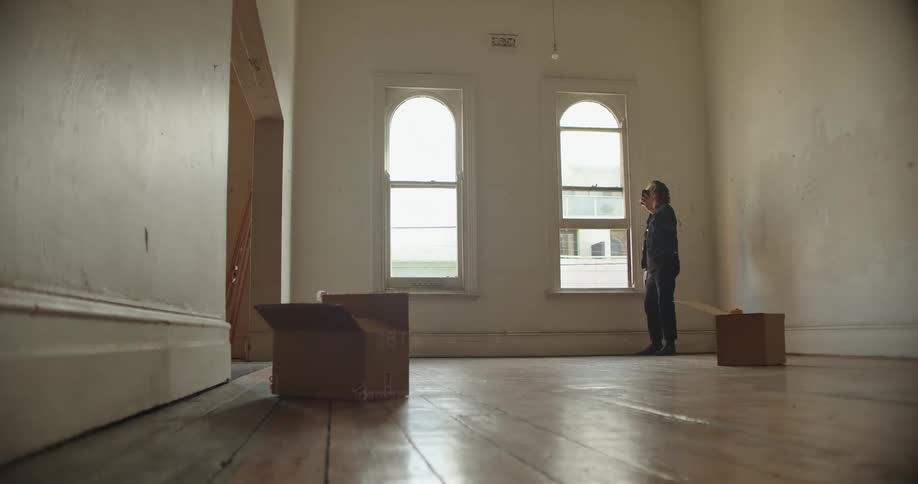 Man with denim jacket and pants makes a video call on smartphone in empty room
