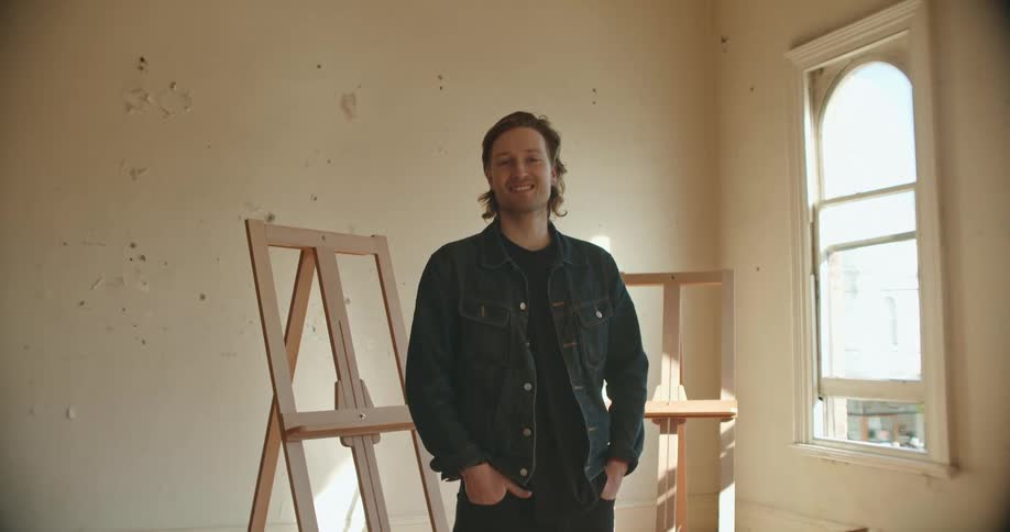 Smiling young man standing inside an empty apartment looking at the camera