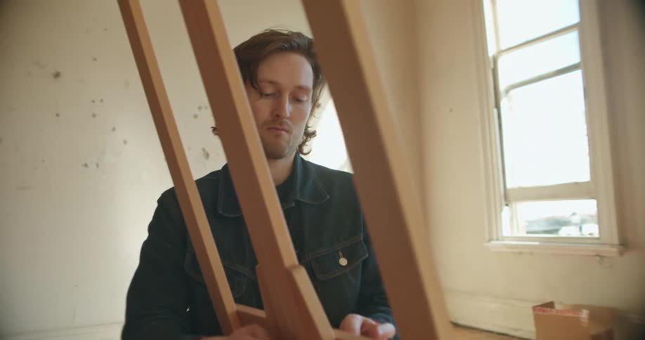 Man assembles a wooden easel in a room