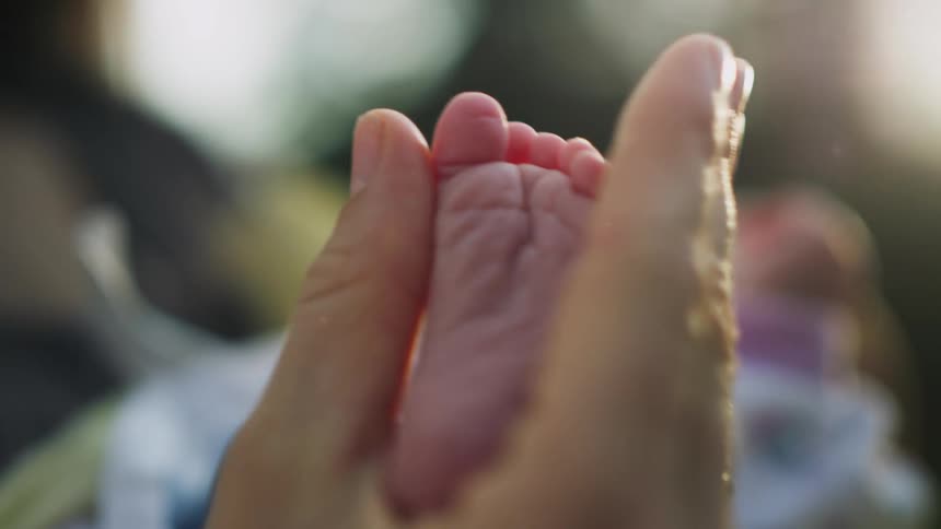 A hand is holding a very tiny baby foot