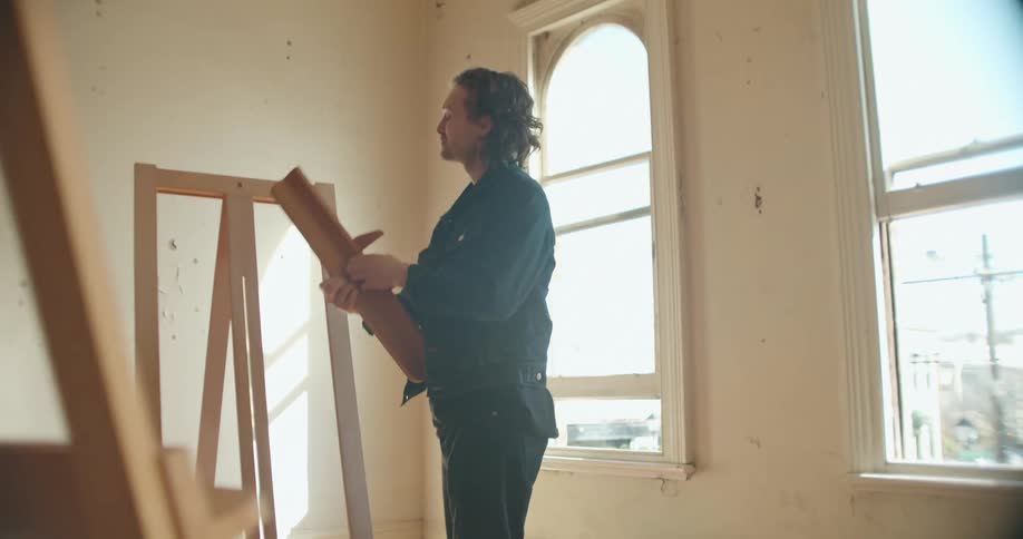 A man picks up a piece of an easel