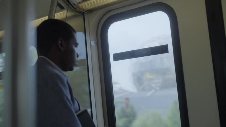 Man looking out the window of a moving train at daytime