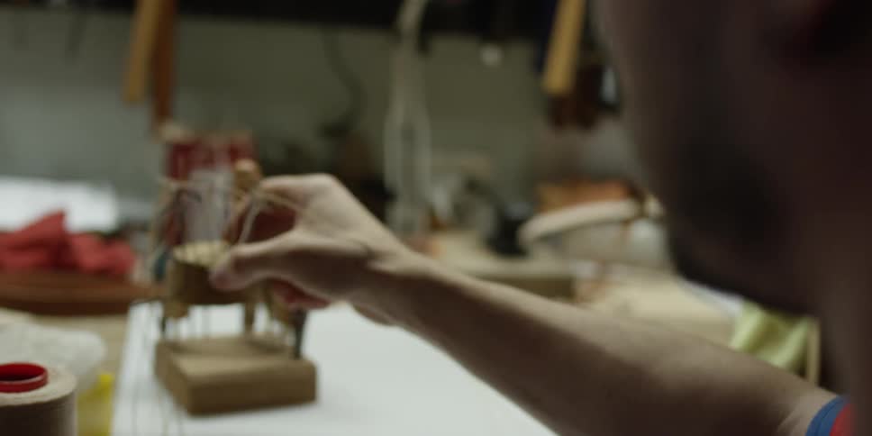 A person picks up a threaded needle in a workshop