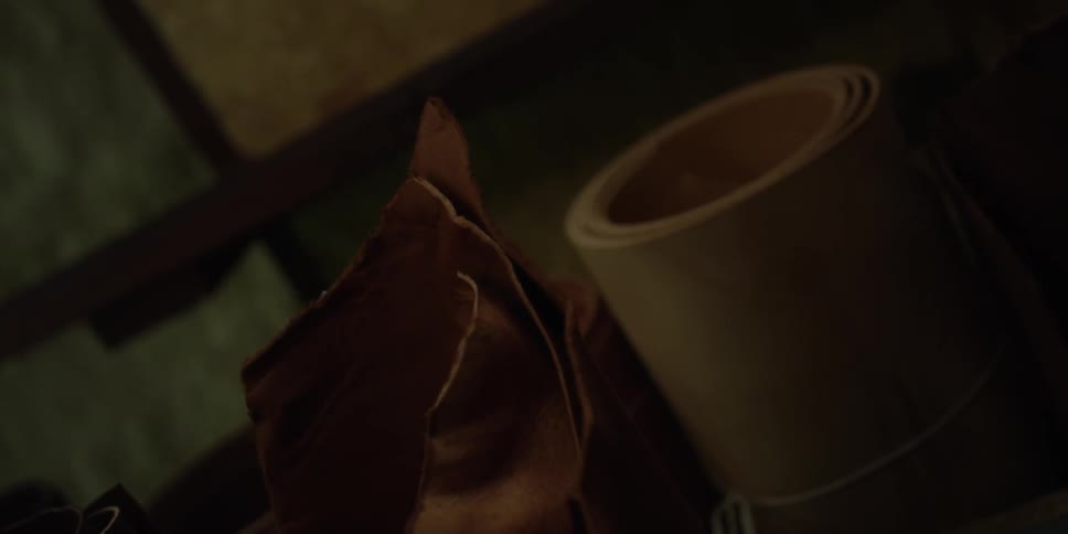 Rolls of leather and paper sit in a dark area