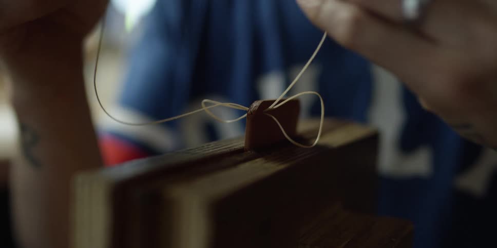 A person stitches a square of leather