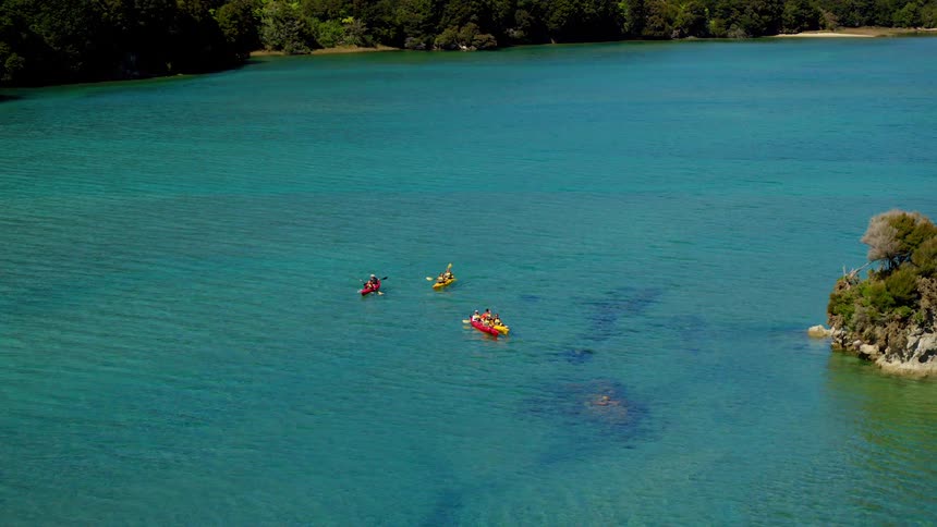 Group of kayaks rowing near an islet over the blue ocean waters near the coast