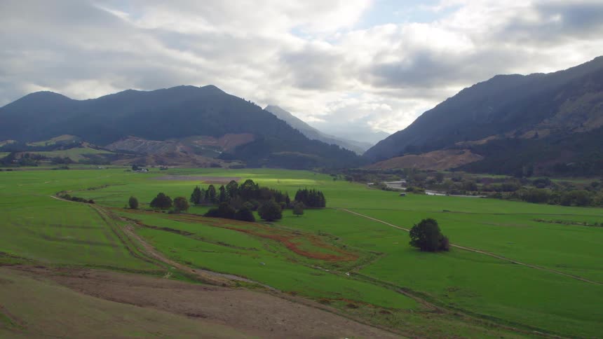 A farmland valley surrounded by mountains on a cloudy day