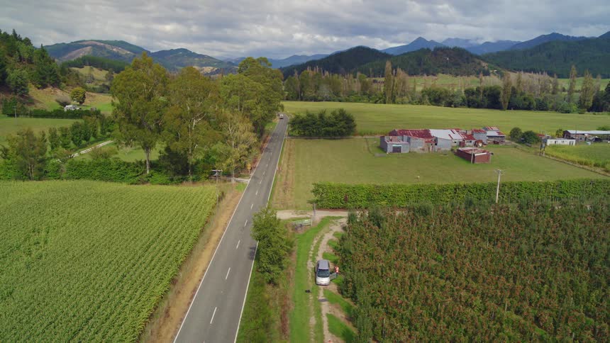 Vehicle driving on a road between small farms and plantations