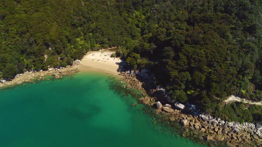 Aerial view of a beach hidden on the coast next to the green ocean water
