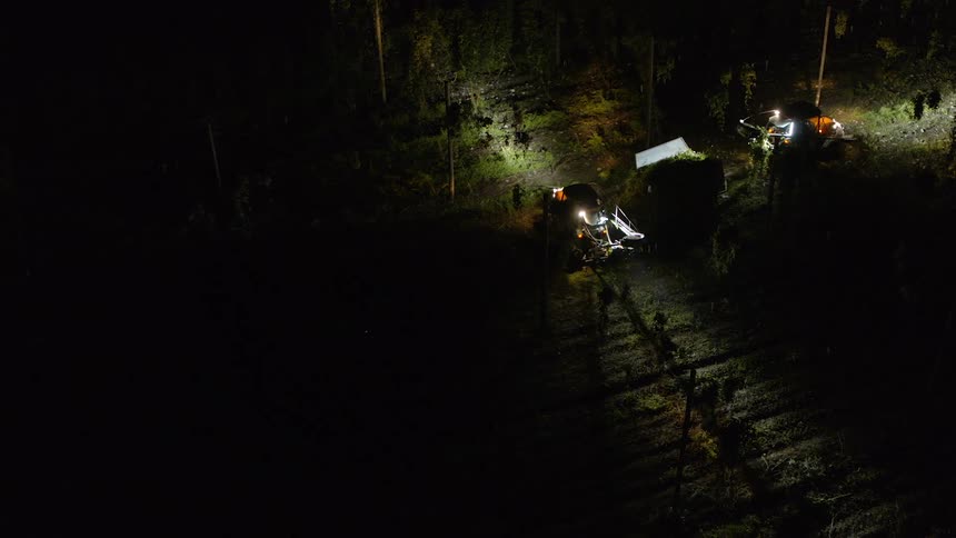 Tractors being operated on a farm outside at night