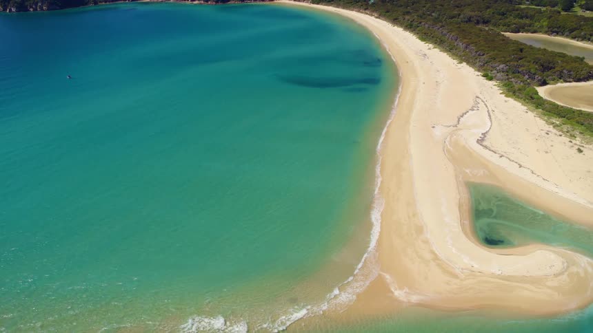 An aerial view of the beach with the ocean crashing against the sand