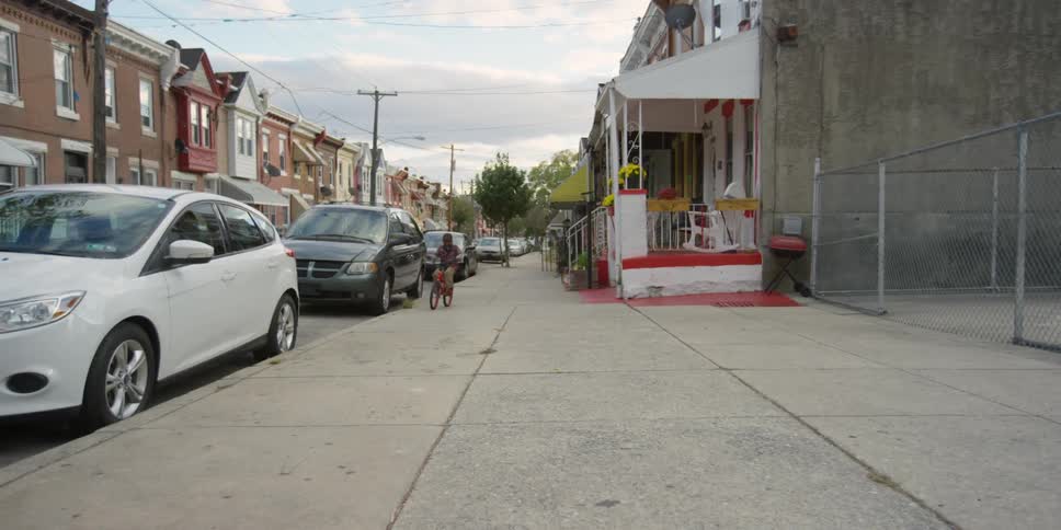 A boy rides his bike down a sidewalk