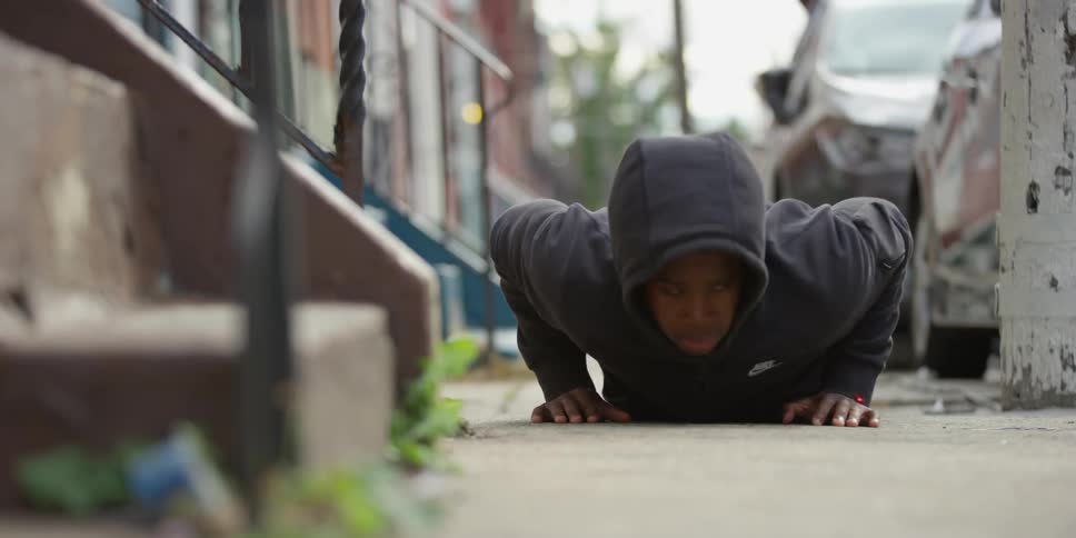 A person does push-ups on the sidewalk