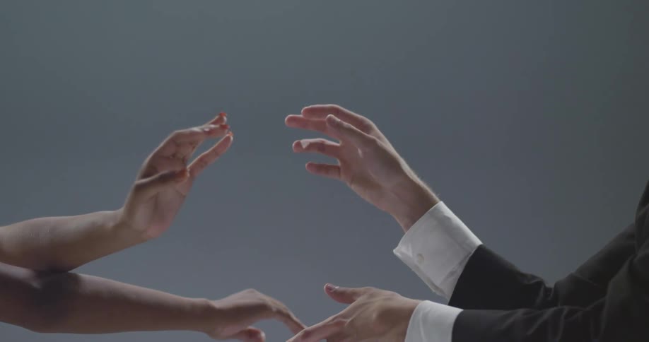 Male and female dancers pose their hands reaching and touching each other
