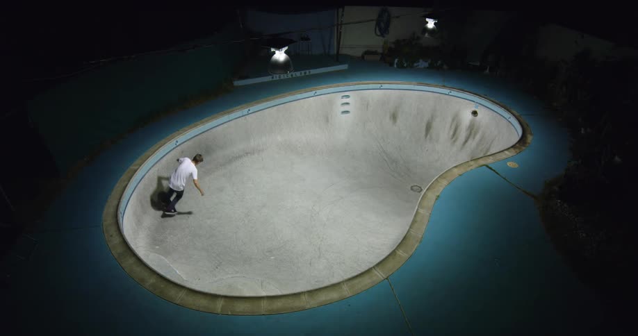 A man that is skateboarding around a pool