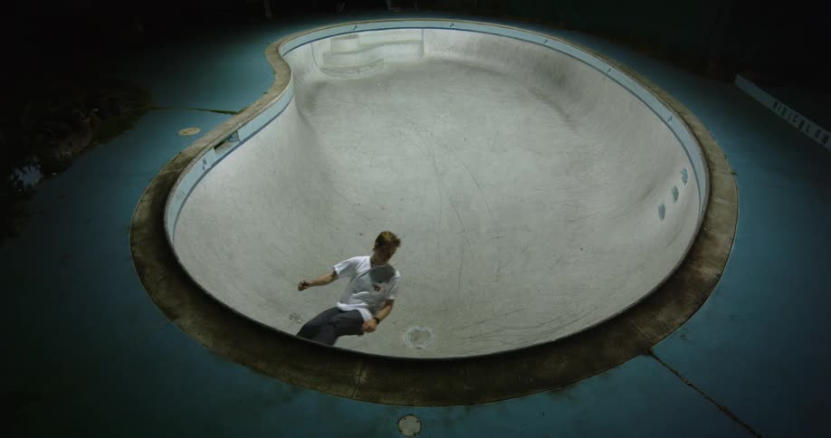 A young man is riding on a skateboard at a skateboard park at night