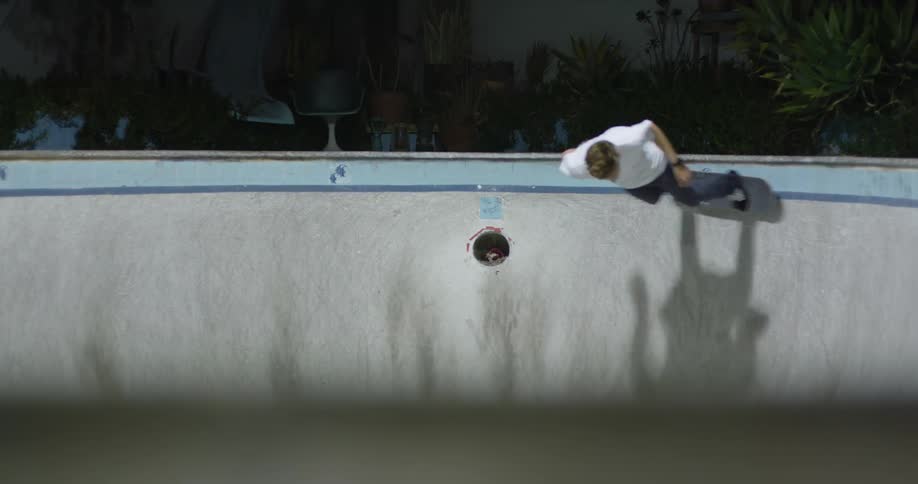 Young man skateboarding inside an empty pool at night