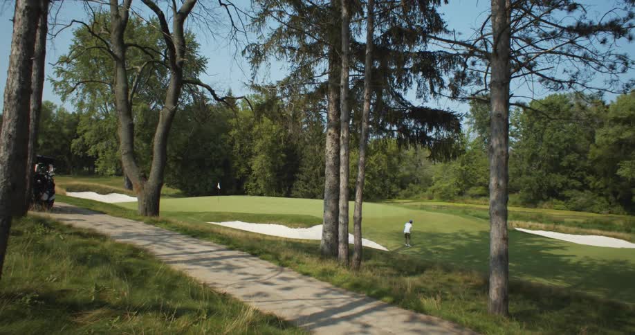 Golfer stands on golfing green taking a swing