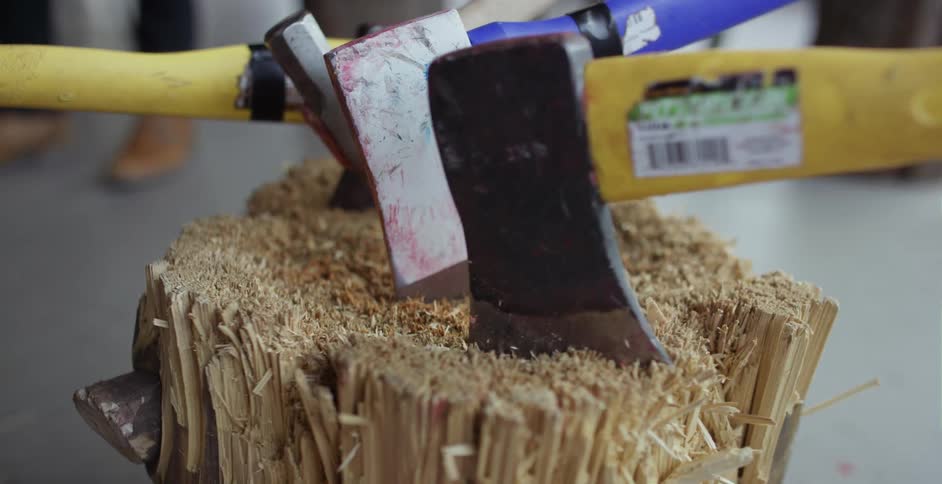 Axes on a piece of wood with people in the background