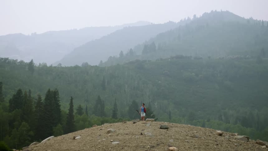 Woman climbs a hill on the mountains carrying an oar in her hands