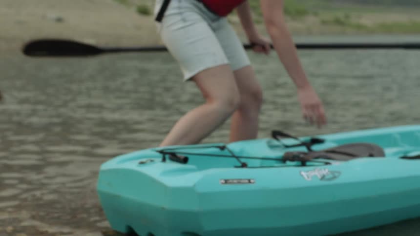 A woman climbing into a kayak on a waterway