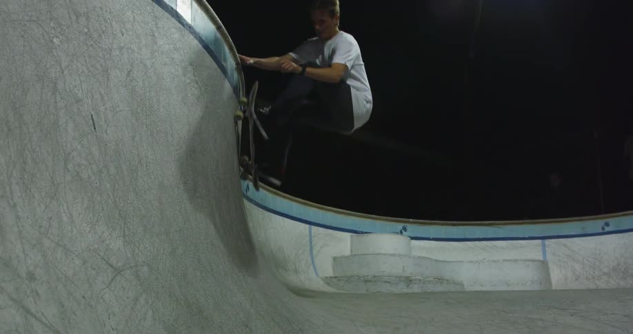 Man rides a skateboard in a skateboard pit at night