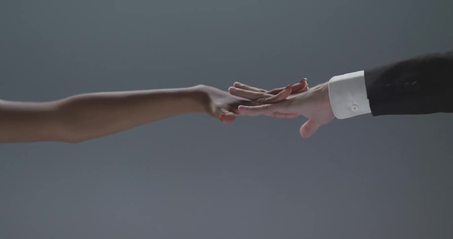 The outstretched arm of a man and woman with their hands linked