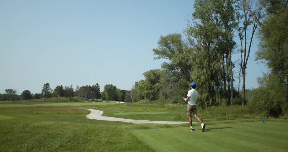 A man is swinging a golf club and hitting a golf ball on a golf course