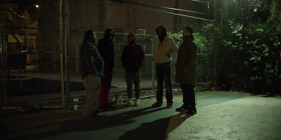 A group of people stand by a fence at night