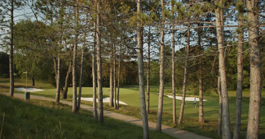 A shot of a golf course where a player can be seen playing at a distance