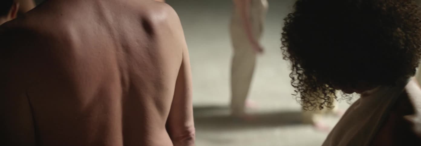 A group of men are standing one after the other semi naked