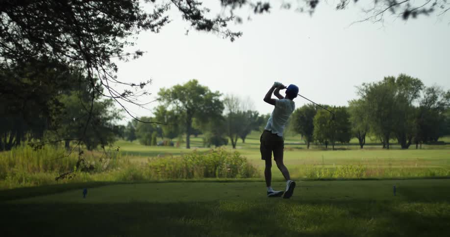Man with cap white shirt and shorts plays hits golf ball with club