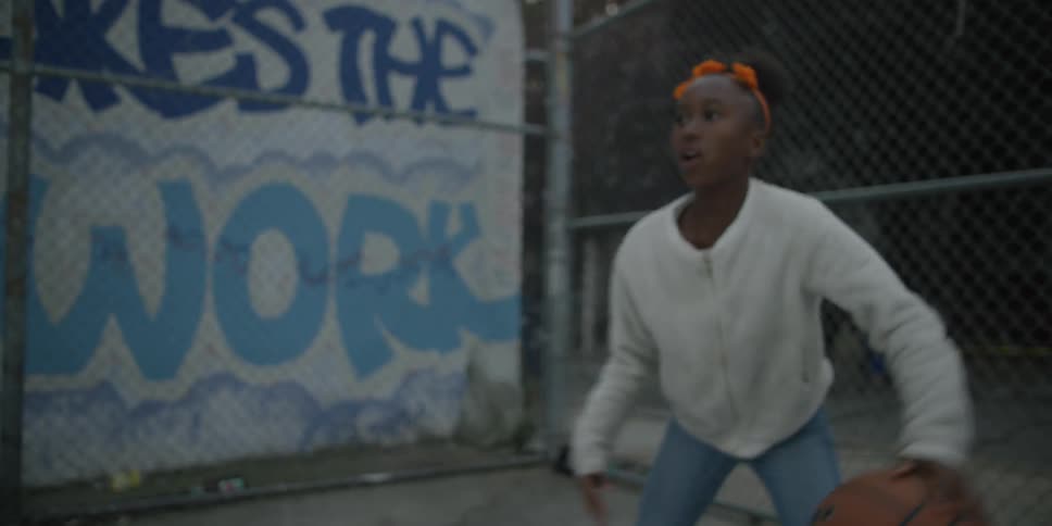 A girl in a sweater plays basketball