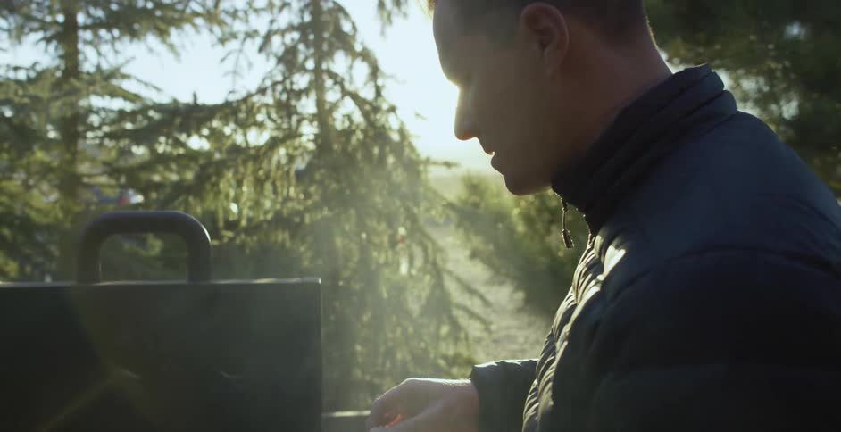 A man is placing hamburger buns on a grill outside