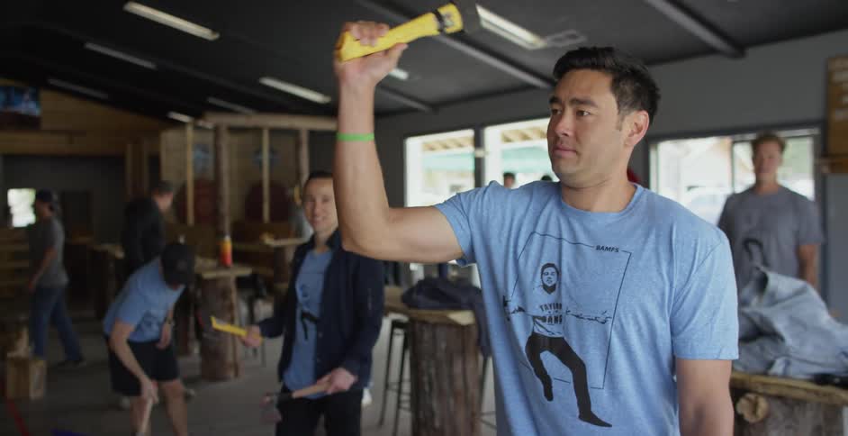 Men are practicing throwing hatchets at targets while indoors during the day