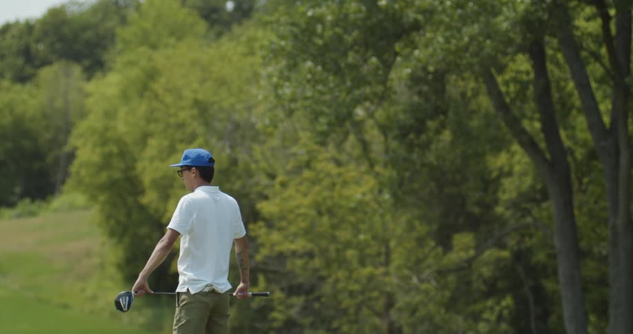 A man is standing on a golf course holding his club in both hands