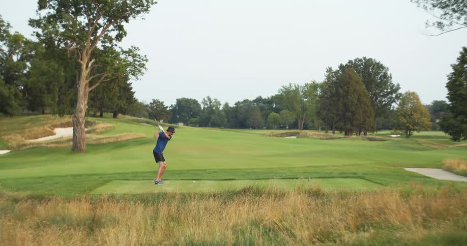 Man standing on a golf course hitting a golf ball