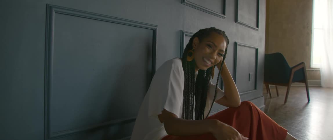 A woman is laughing as she sits by the wall