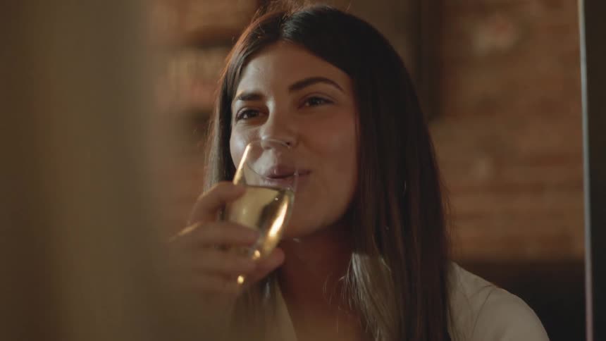 Woman drinking champagne from a tall glass on a party with friends