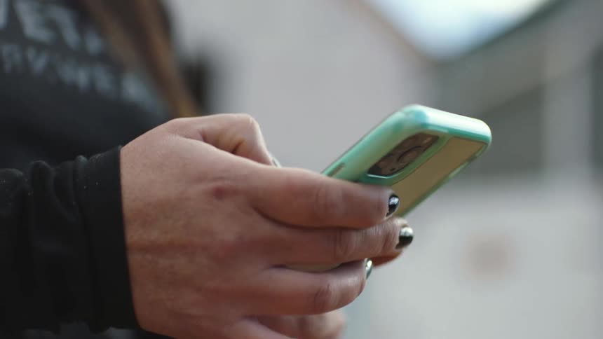 A woman is typing on her cell phone