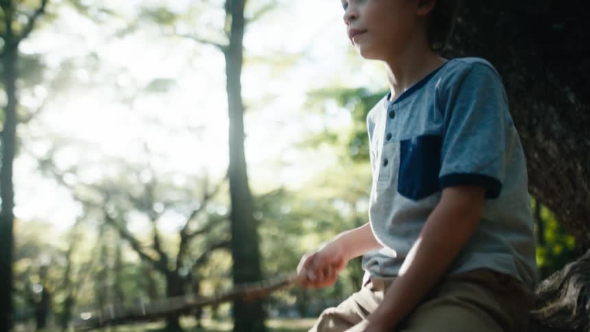 Young boy sits on a log and taps it with a stick as he pretends hes riding a horse
