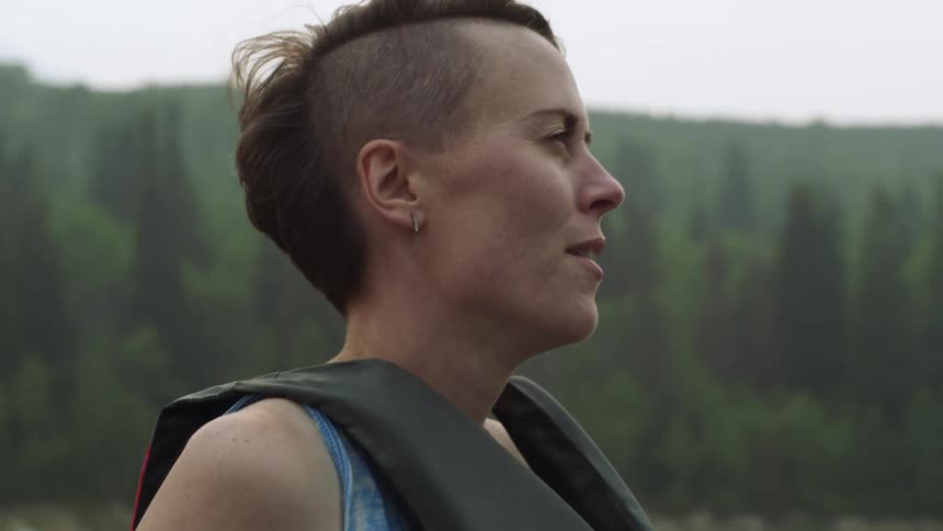 Young woman wears a life jacket outdoors near the forest