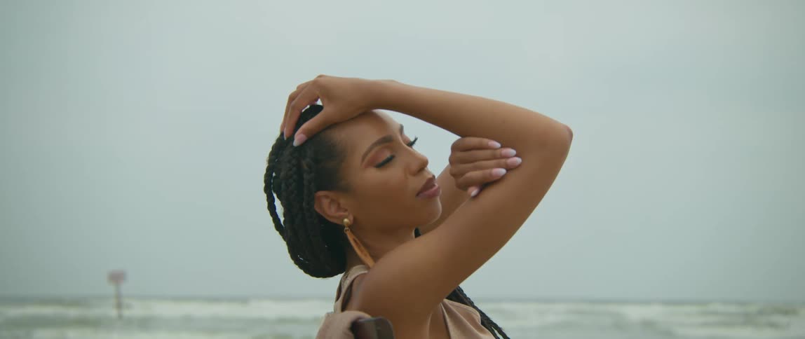 A woman on a beach with the ocean sky and clouds in the background